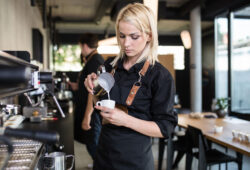 Baristka nalévá našlehané mléko do šálku