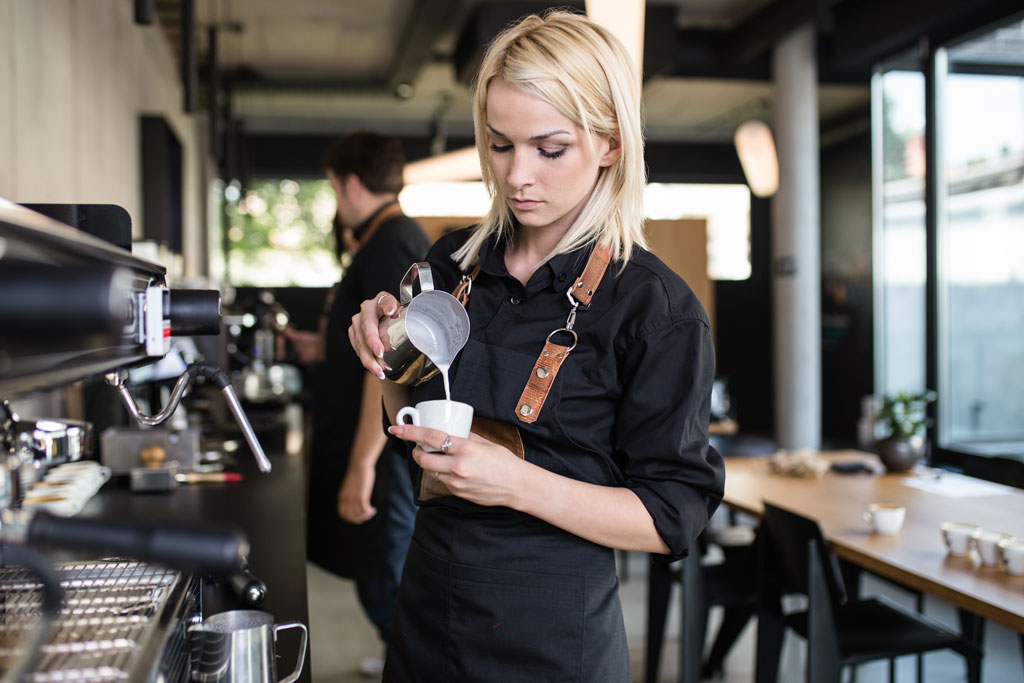 Baristka nalévá našlehané mléko do šálku
